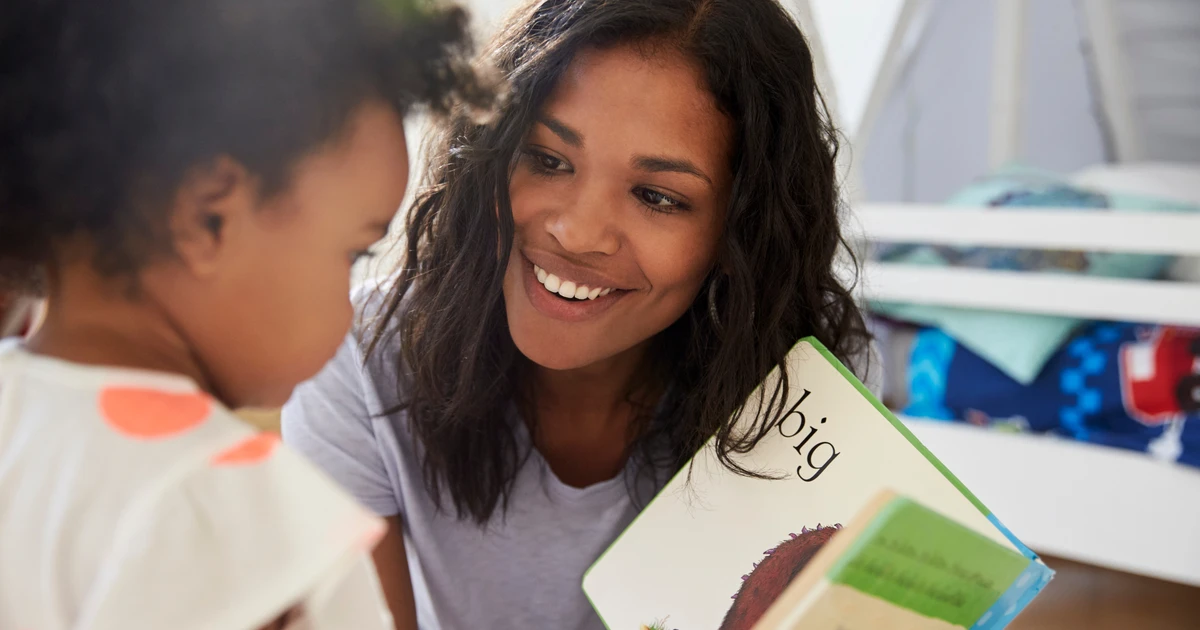 A woman holding a book open for a young child