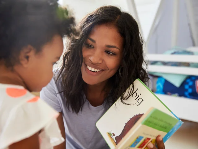 A woman holding a book open for a young child