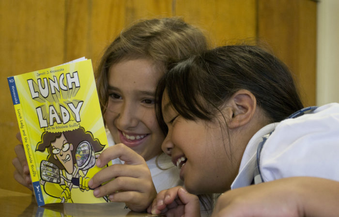 Girls sharing a book at a First Book distribution in California.