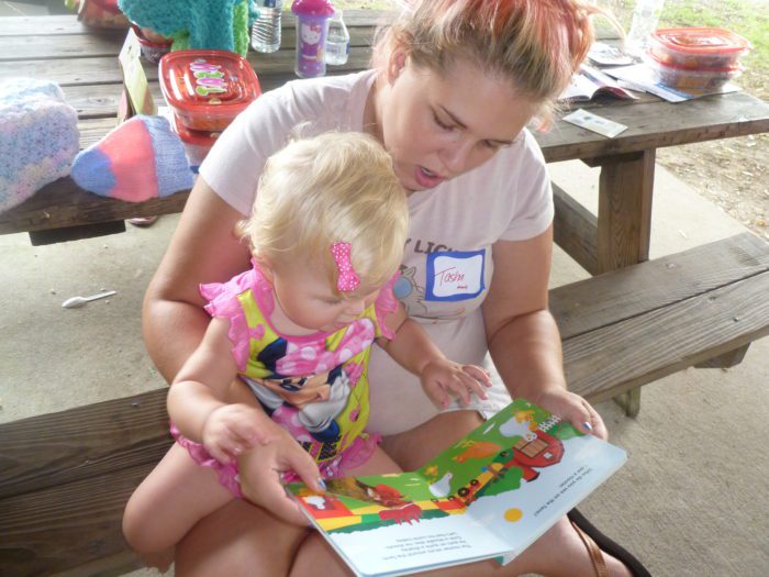 woman reading with a child at a picnic table