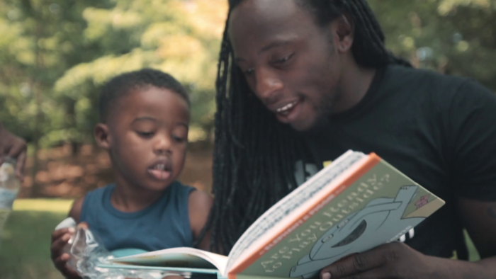 black father reading elephant and piggy to his son