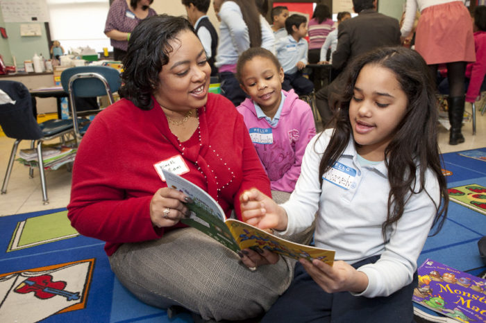 black teacher reading with two black students