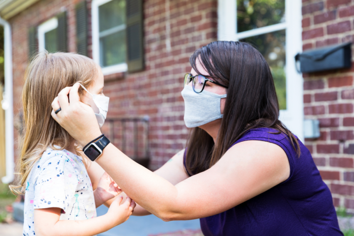 woman helping a young child with mask