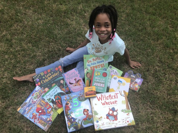 young black student with lots of books on the grass