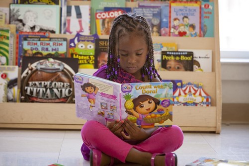 young black girl reading a dora explorer book