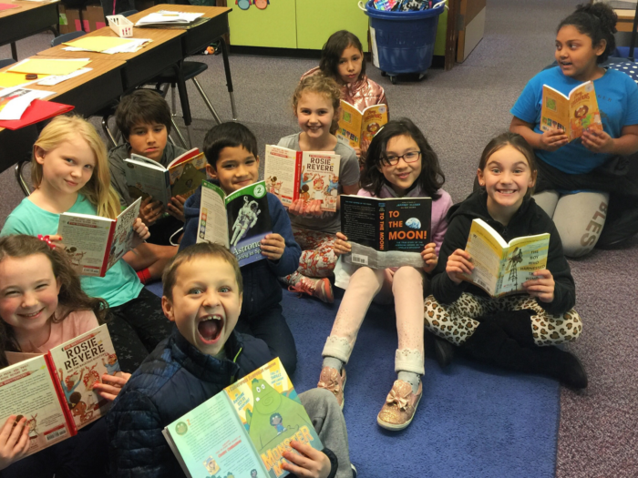 happy children reading STEM books in the classroom