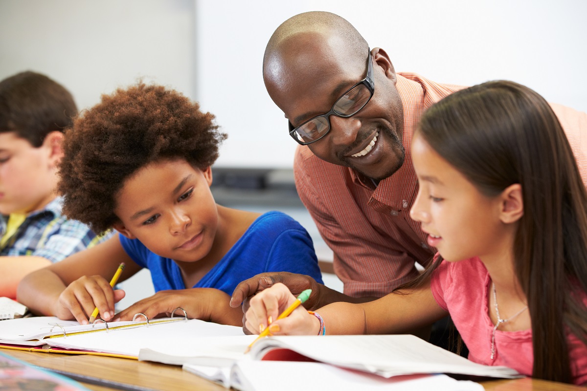 black educator working with a black and brown student in the classroom