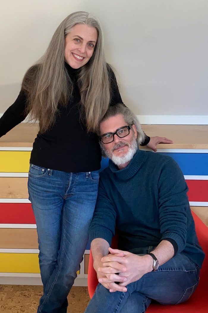 Mo & Cher Willems standing together in front of a colorful wall.