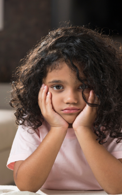 young hispanic girl, head in hands and looks sad
