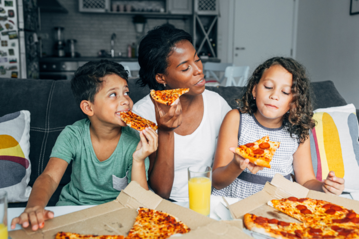 mother and two kids eating pizza at home