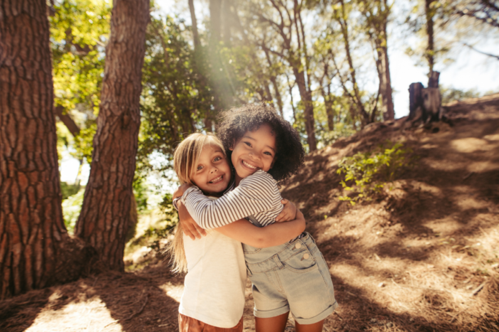 Two young girls hugging in nature
