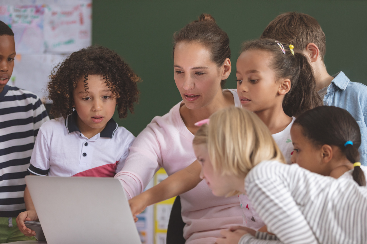 children and teacher gathered around a laptop