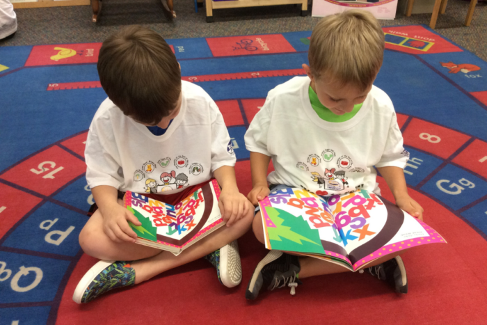 two boys reading their storybook treasure books with matching shirts