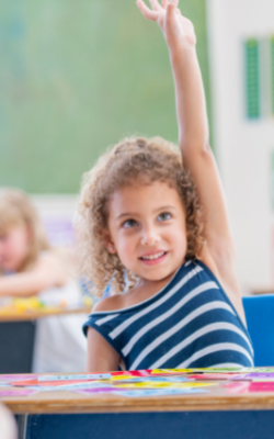 child raising their hand in a classroom