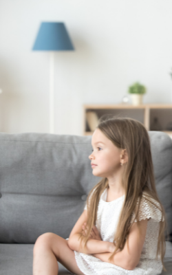 child sitting on a couch with crossed arms and a bad attitude