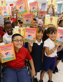 group of diverse kids holding up books and smiling