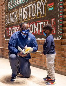 black teacher speaking to young black student with books