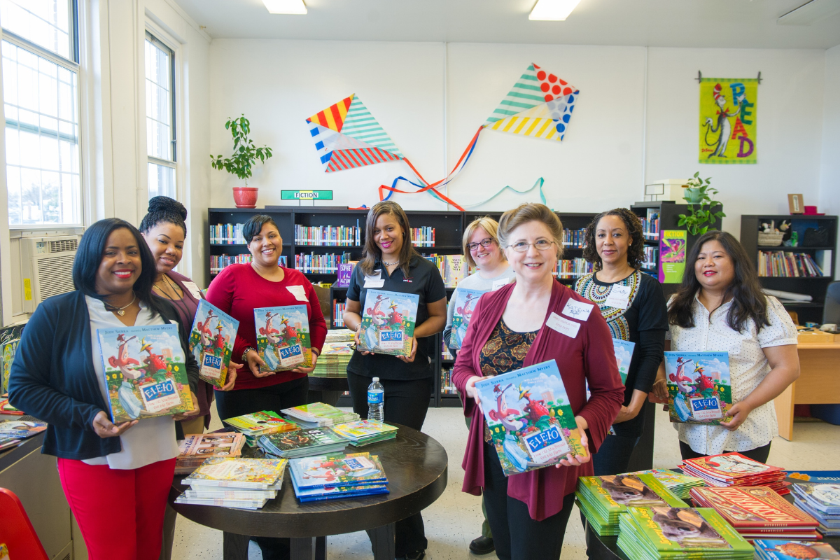 group of educators in a school library holding new books