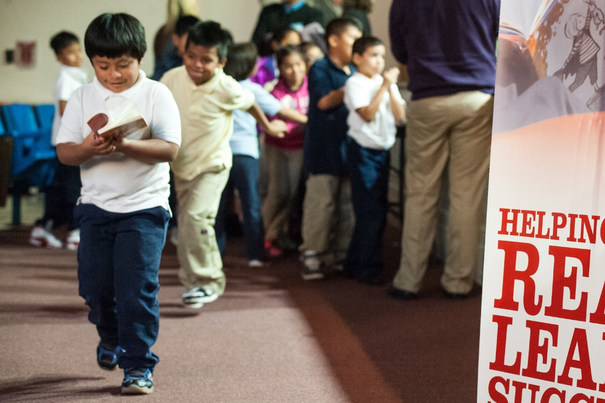 Boy walks away from book distribution line with a book