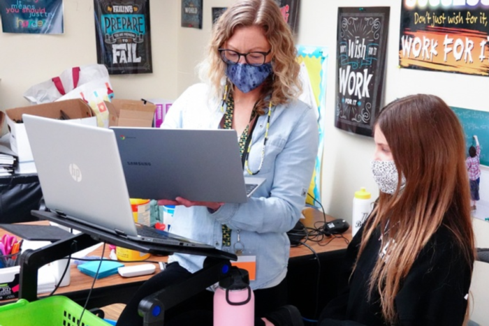 educator helping student with laptop - mask covid