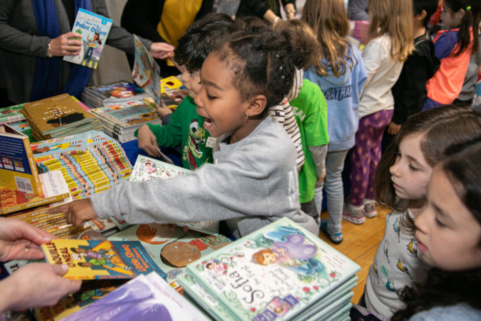 african american girl excited pointing at book stacks