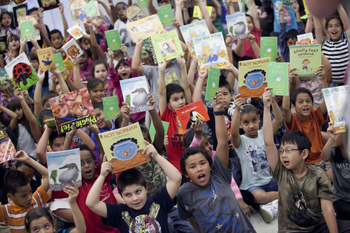 large group of kids holding up books