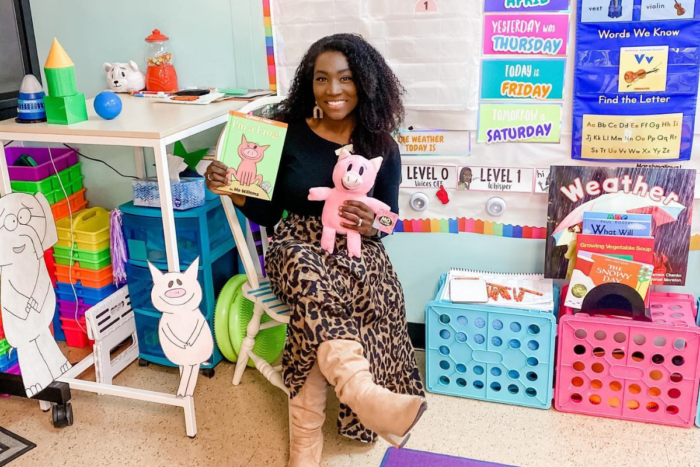 teacher holding Mo Willems' Piggie and Elephant book and a piggie plush toy