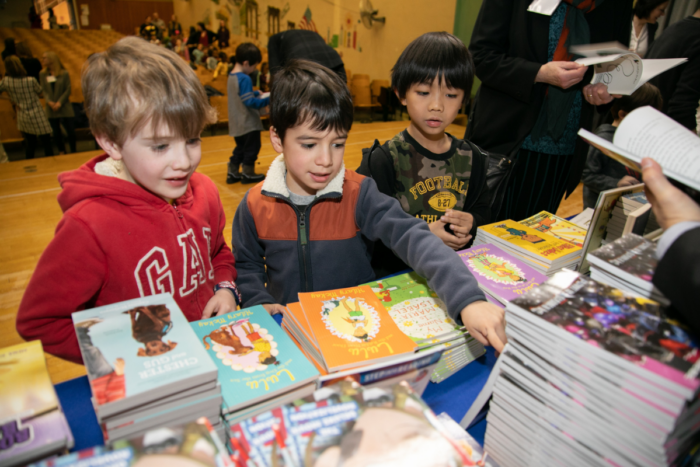 group of kids looking at a wide selection of books on a table