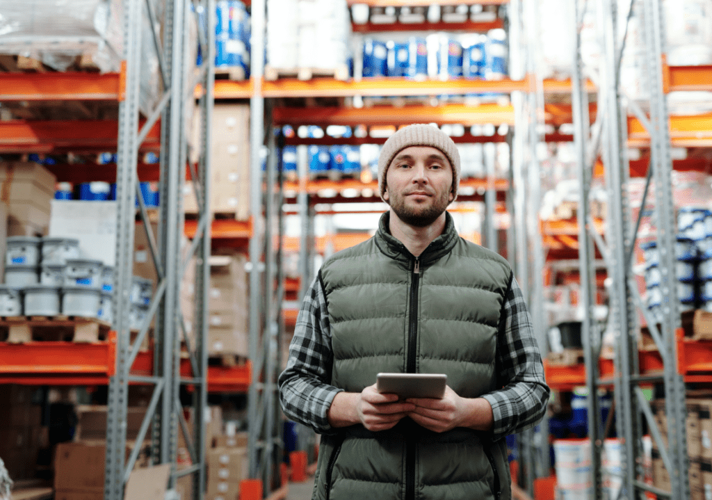 man standing in a warehouse holding a tablet