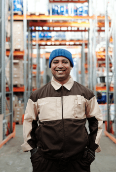 man standing in a shipping warehouse, smiling