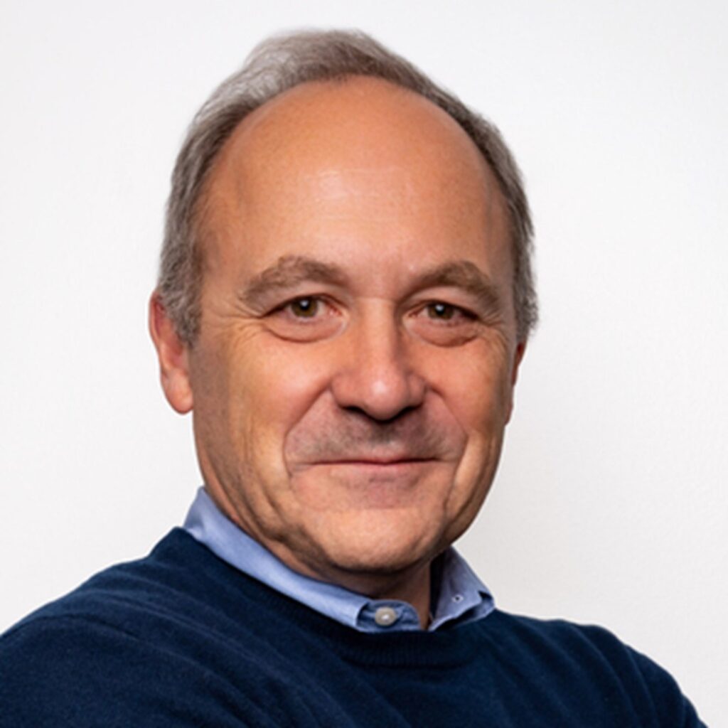 professional headshot image of Etienne Veber, wearing a light blue button up with a dark blue sweater. 