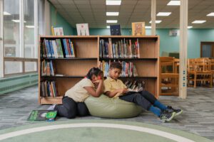 two students at library reading a book