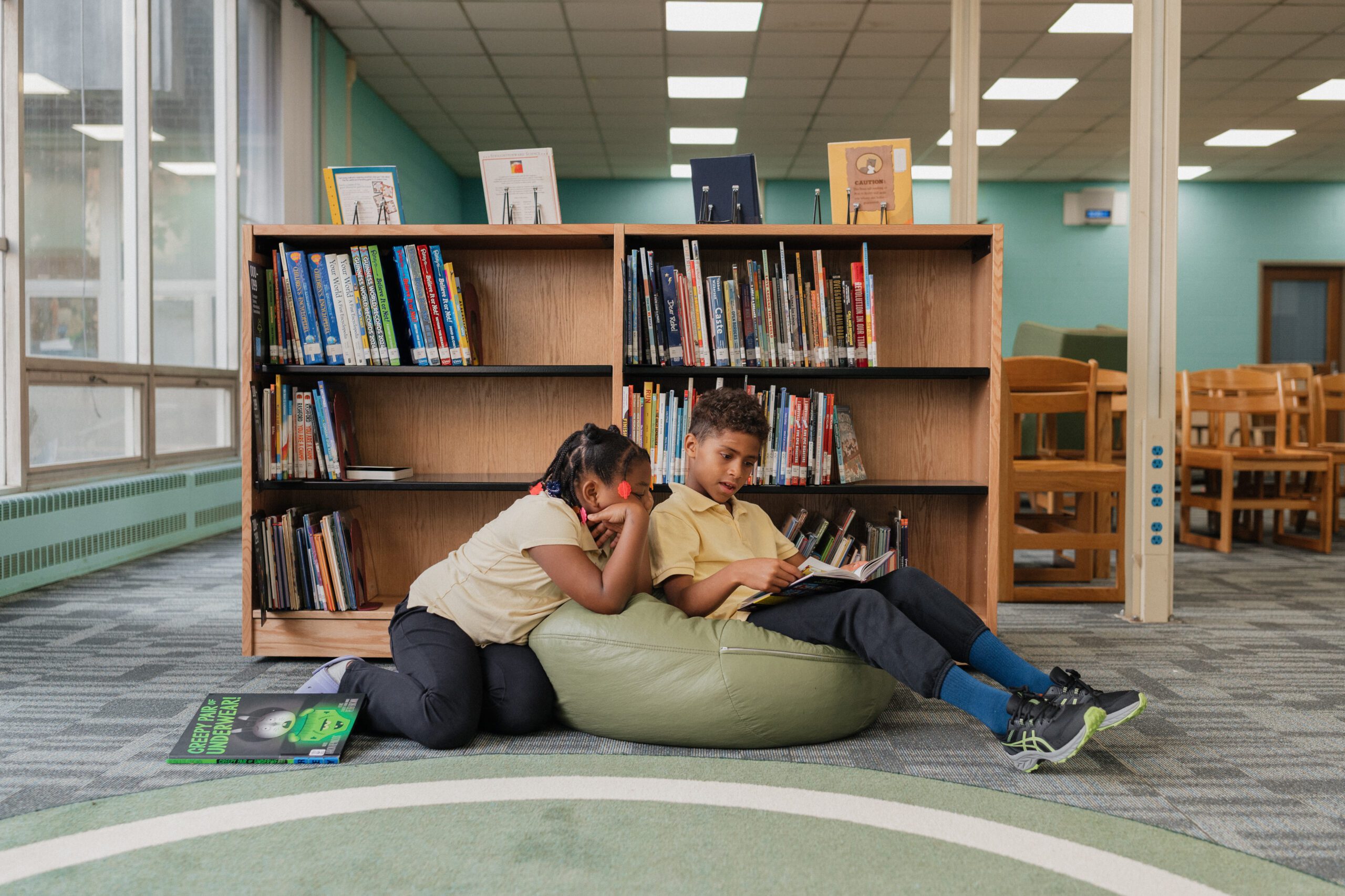 two students at library reading a book