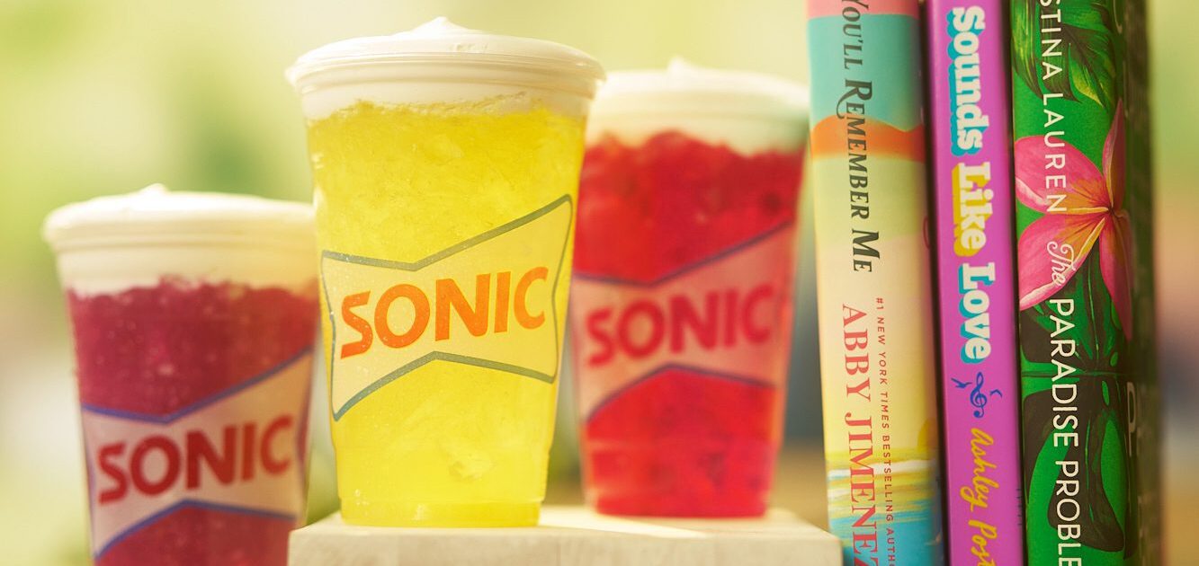 image of 3 drink cups from Sonic's new Sweet Topped Lemonades next to 3 books by authors Christina Lauren, Abby Jimenez, and Ashley Poston.